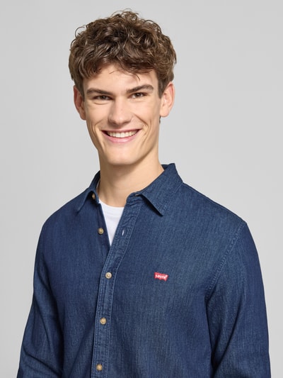 Męski model nosi Freizeithemd in Denim-Optik od Levi's®, niebieski denim, regular fit, kołnierz Kent, zbliżenie na górną część ciała.