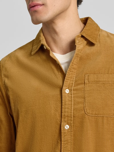 Mannenmodel draagt Regular Fit Cordhemd met borstzak van Scotch & Soda in puur katoen, Kentkraag, labelpatch, detailopname bovenlichaam. Ruglengte maat M 78 cm, schouderbreedte 46 cm, mouwlengte 66 cm.