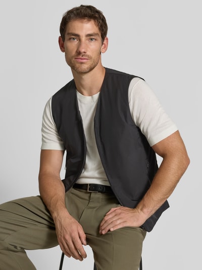 Männermodel trägt Regular Fit Weste mit V-Ausschnitt Modell 'Marve' von Tiger of Sweden in Dunkelgrau mit Reißverschluss und Eingrifftaschen, Ganzkörperansicht von vorne.