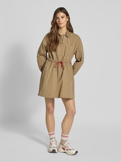 Frauenmodel trägt Minikleid mit Hemdblusenkragen und Reißverschluss von Jake*s Casual aus Baumwoll-Mix, A-Linie, Eingrifftaschen, Bindegürtel, sandfarben, strukturierte Oberfläche, Ganzkörperansicht von vorne.