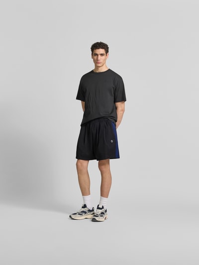 Männermodel trägt Shorts mit Logo-Stitching von Kenzo, Straight Fit, elastischer Bund, Gesäßtaschen, Eingrifftaschen, schwarz, Ganzkörperansicht von vorne.