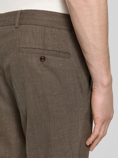 Männermodel trägt Slim Fit Stoffhose mit Woll-Anteil Modell 'Cole' von CG - Club of Gents, Detailaufnahme Gesäßtasche von schräg hinten, brauner Anzug-Stoff mit feiner Textur, Bügelfalten, Elastischer-Material-Mix, Eingriffstaschen, Knopf-Gesäßtasche, Knopf-Reißverschluss, Bundweite 47 cm, Innenbeinlänge 70 cm in Größe 50.