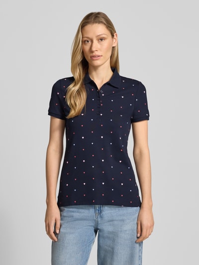Modelka kobieca nosi Poloshirt mit Polokragen und kurzer Knopfleiste von Christian Berg Woman, bawełniany miks ze stretchem, krój regular fit, granatowy z drobnymi kolorowymi sercami, długość tyłu w rozmiarze S: 62 cm, widok całej sylwetki z przodu.