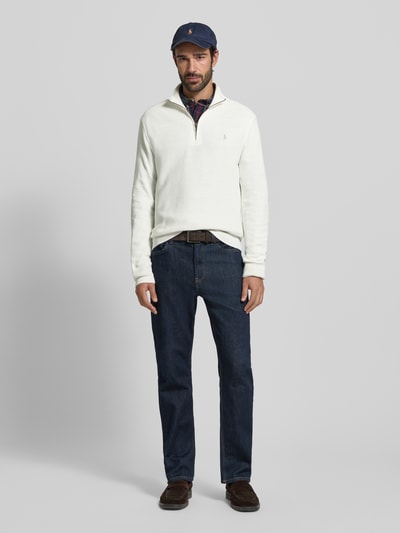 Männermodel trägt Regular Fit Troyer mit Label-Stitching von Polo Ralph Lauren aus reiner Baumwolle in Weiß, Gerippte Abschlüsse, Troyer-Kragen, kurzer Reißverschluss, Rückenlänge 70 cm, Ärmellänge 68 cm, Ganzkörperansicht von vorne.