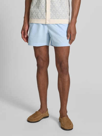 Männermodel trägt Badehose mit elastischem Bund und Gesäßtasche von MCNEAL in Hellblau, Regular-Fit, Tunnelzug, Ganzkörperansicht von vorne.