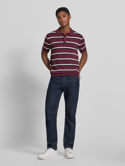 Männermodel trägt Regular Fit Poloshirt mit polokraag van Christian Berg Men, puur katoen, korte knoopsluiting, horizontale strepen, ruglengte maat M 68 cm, mouwlengte maat M 25 cm, donkere jeans, witte sneakers, geheel in beeld van voren.