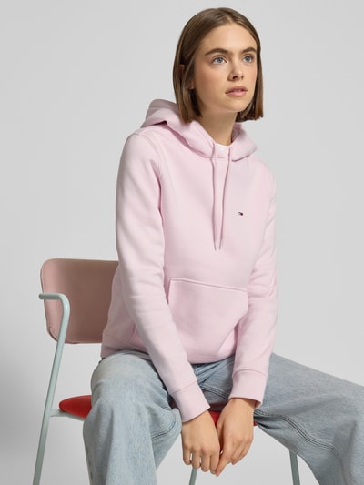 Modelka kobieca nosi Regular Fit Hoodie aus Baumwoll-Mix od Tommy Jeans w jasnoróżowym kolorze, jednolita optyka, widok górnej części ciała z przodu.