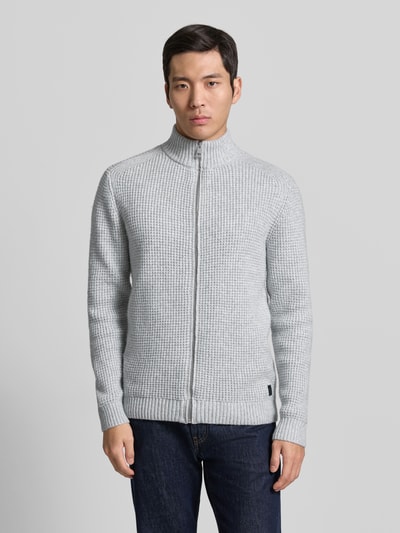 Männermodel trägt Regular Fit Strickjacke mit Woll-Anteil von Tom Tailor in grauer Melangeoptik, Reißverschluss, Stehkragen, Ganzkörperansicht von vorne.