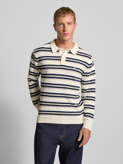 Männermodel trägt Strickpullover mit Polokragen in Bouclé-Optik von Review, Regular-Fit, Streifenmuster, Knopfleiste, Label-Stitching, Ganzkörperansicht von vorne.