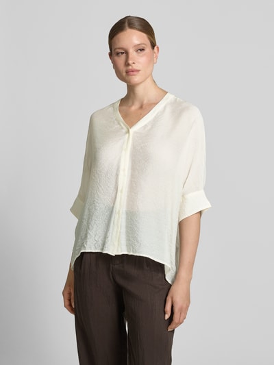 Modelka nosi Relaxed Fit Bluse aus Viskose-Mix mit 3/4-Arm von comma w kolorze kremowym, dekolt w serek, listwa guzikowa, krój relaxed fit, mieszanka wiskozy, długość tyłu w rozmiarze S: 62 cm, długość rękawa w rozmiarze S: 18 cm, tekstura lekko pognieciona; zdjęcie całej sylwetki z przodu.