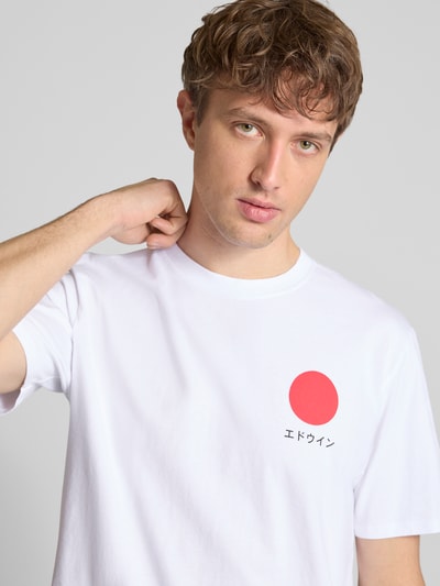 Męski model nosi białe T-Shirt aus reiner Baumwolle Modell 'JAPANESE SUN' od Edwin, okrągły dekolt, prosty krój, nadruk z czerwonym kołem, widok na górną część ciała z przodu.