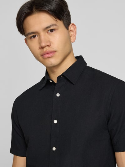 Männermodel trägt Regular Fit Freizeithemd aus Baumwoll-Leinen-Mix von Jack & Jones in Schwarz, Nahaufnahme Oberkörper, Kentkragen, Knopfleiste.