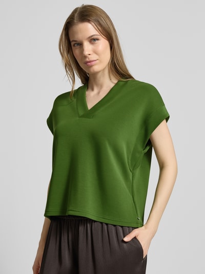 Vrouwenmodel draagt Relaxed fit T-shirt met lyocell-aandeel model 'Tencel' van Scotch & Soda in groen, elastische materiaalmix, V-hals, kapmouwen, nahaufnahme bovenlichaam.