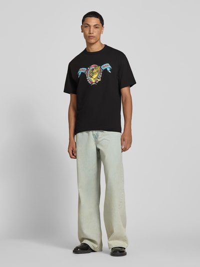 Männermodel trägt Regular Fit T-shirt uit puur katoen van Kenzo, zwarte kleur, labelprint, korte mouw, ronde hals, ruglengte maat M 69 cm, ganzkörperaanzicht van voren