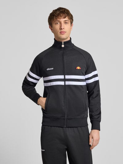 Męski model nosi bluza rozpinana z mieszanki bawełny model 'RIMINI' od Ellesse, prosty krój, stójka, detale z logo, czarny, długość tyłu w rozmiarze M: 71 cm, długość rękawa: 43 cm, całkowity widok z przodu