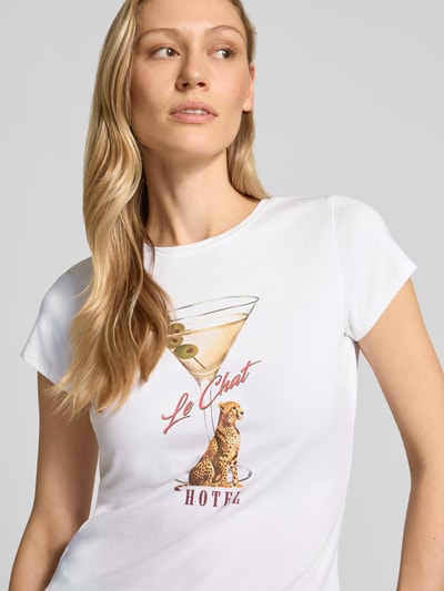 Frauenmodel trägt T-Shirt mit Label-Detail Modell 'LEOPARDTINI' von Guess, weiß, eng geschnitten, Rundhals, Nahaufnahme Oberkörper.