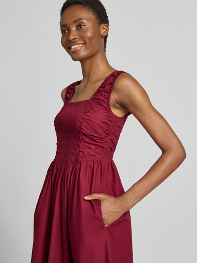 Frauenmodel trägt Cocktailkleid mit Karree-Ausschnitt Modell 'WIMI' von YAS in Dunkelrot, Baumwolle, Smok-Details, Nahaufnahme Oberkörper.