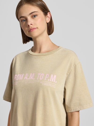 Frauenmodel trägt T-Shirt mit Rundhalsausschnitt Modell 'AM to PM' von OH APRIL, beige, Baumwolle, Oversized, Print, Nahaufnahme Oberkörper.