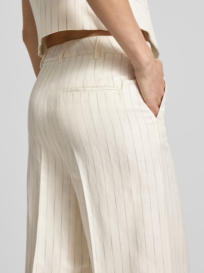 Frauenmodel trägt Wide Fit Stoffhose mit Bügelfalten von Christian Berg Woman Selection, cremefarben mit feinen Nadelstreifen, Gesäßtasche, Nahaufnahme Hüfte