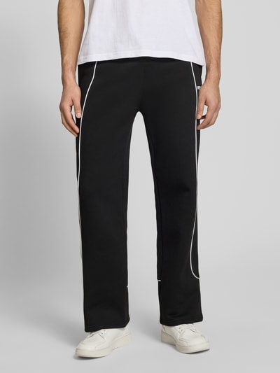 Männermodel trägt Sweatpants mit elastischem Bund und Logo von REVIEW, czarne spodnie dresowe z bawełny, krój relaxed fit, logo, długość wewnętrzna nogawki w rozmiarze M: 78 cm, Ganzkörperansicht von vorne