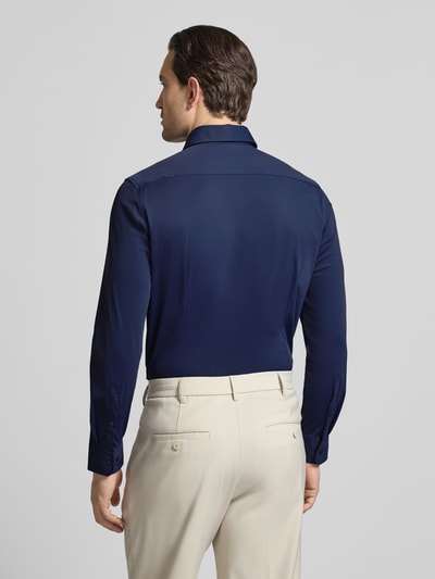 Männermodel trägt Slim Fit Business-Hemd mit Haifischkragen von SEIDENSTICKER, dunkelblau, weiche Textur, Stretch-Anteil, Ganzkörperansicht Rückansicht