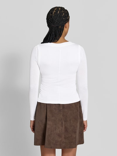 Frauenmodel trägt Longsleeve aus Viskose-Mix von BAUM & PFERDGARTEN, Weiß, enge Passform, Ziernaht, 2-in-1-Look, Ganzkörperansicht Rückansicht.