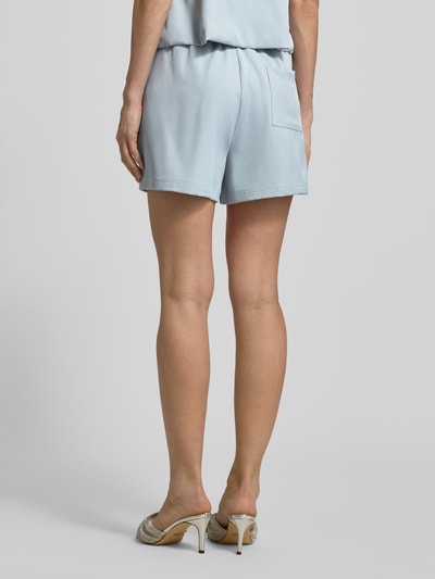 Frauenmodel trägt Shorts mit Falten und Eingrifftasche von Little Mistress in Hellblau, Material-Mix mit Stretch, Ganzkörperansicht Rückansicht.