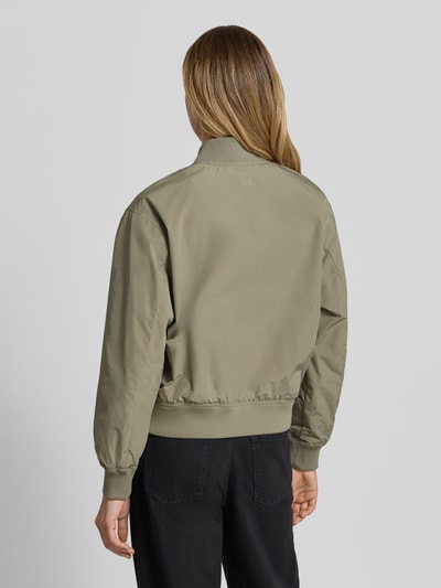 Frauenmodel trägt Regular Fit Jacke mit Stehkragen von camel active in Olivgrün, elastische Abschlüsse, Rückenansicht, Ganzkörperansicht Rückansicht.