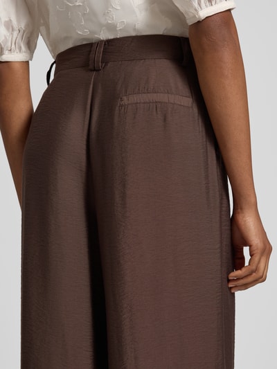 Frauenmodel trägt Wide Fit Hose aus Viskose-Mix Modell 'Finja' von GUIDO MARIA KRETSCHMER WOMAN, braun, strukturierte Oberfläche, Detailaufnahme Rückansicht, Bundfalten, Haken- und Reißverschluss, Bundweite 37 cm, Innenbeinlänge 78 cm.