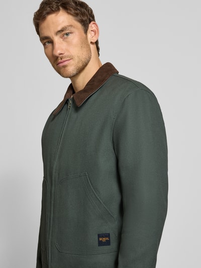 Männermodel trägt Regular Fit Jacke aus reiner Baumwolle von MCNEAL in Dunkelgrün mit Umlegekragen und Einstecktaschen, Nahaufnahme Oberkörper, Rückenlänge 67 cm, Schulterbreite 53 cm, Brustweite 60 cm, Ärmellänge 66 cm.