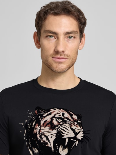 Männermodel trägt Regular Fit T-Shirt mit Motiv-Print von Antony Morato, Schwarz, Rundhalsausschnitt, Baumwoll-Mix, Nahaufnahme Oberkörper. Rückenlänge bei Größe M: 64 cm.