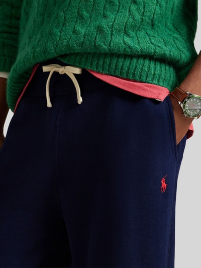 Mężczyznamodel nosi Regular Fit Sweatshorts aus Baumwoll-Mix od Polo Ralph Lauren, niebieski kolor, logo, kieszenie boczne, detal tunelowy, bawełniana faktura, krój regular fit, ujęcie: zbliżenie na górną część ciała.