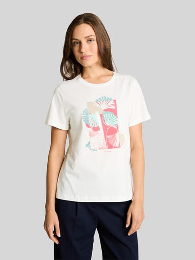Modelka nosi Regular Fit T-Shirt aus reiner Baumwolle von Tom Tailor, biały, unikatowy nadruk graficzny, krótki rękaw, okrągły dekolt, widok całej sylwetki z przodu
