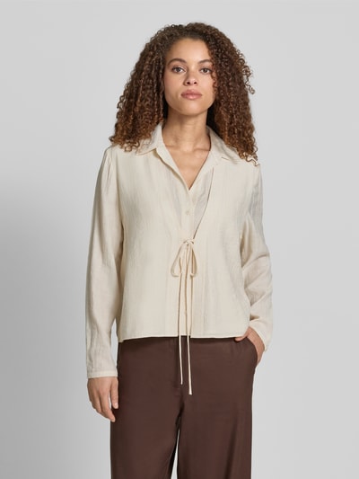 Frauenmodel trägt Bluse aus Viskose-Mix mit Binde-Detail von Jake*s Collection in Beige, Umlegekragen, Knopfleiste, Straight Fit, Ganzkörperansicht von vorne. Rückenlänge 55 cm, Ärmellänge 62 cm bei Größe 38, feine Struktur.