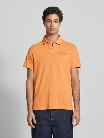 Männermodel trägt Regular Fit Poloshirt aus reiner Baumwolle von Replay in Orange mit Label-Stitching, Kurzärmelig, Ganzkörperansicht von vorne.