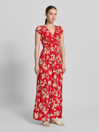 Vrouwenmodel draagt Maxikleid aus Viskose mit V-Ausschnitt und Smok-Details van Apricot, rood met bloemenprint, getailleerd model, zuiver viscose, V-hals, smokdetail, ruglengte maat S 121 cm, borstwijdte maat S 38 cm. Ganzkörperansicht van voren.
