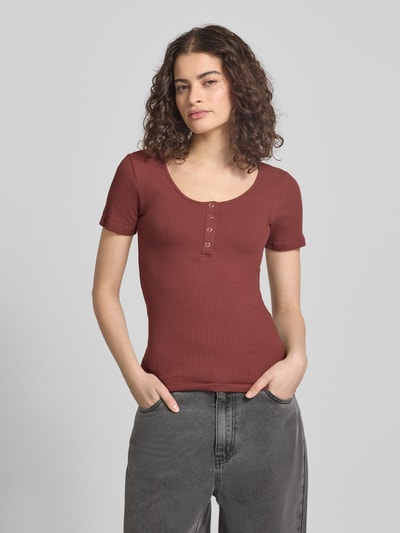 Modelka nosi Slim Fit T-Shirt aus Baumwoll-Mix Modell 'KITTE' od Pieces, brązowy, krótki rękaw, prążkowana bawełna, unikolor, u-neck, krój slim fit, widok całej sylwetki z przodu.
