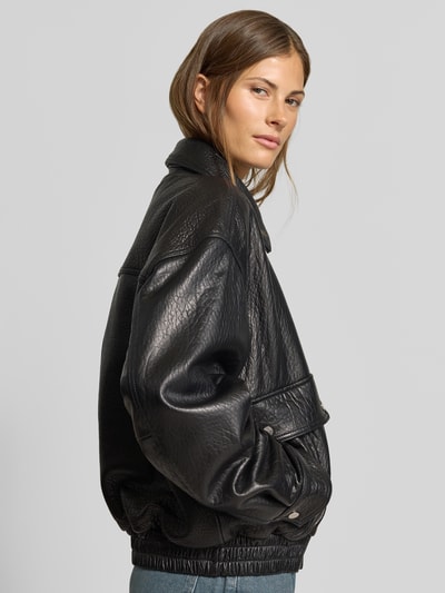 Frauenmodel trägt schwarze Regular Fit Bomberjacke mit Umlegekragen von MYON, strukturierte Lederoptik, Eingrifftaschen, Nahaufnahme Oberkörper.