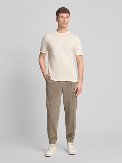 Männermodel trägt Regular Fit Stoffhose aus Viskose-Mix mit elastischem Bund von ARMANI EXCHANGE in Beige, Ziernähte, Gesäßtaschen, Ganzkörperansicht von vorne.
