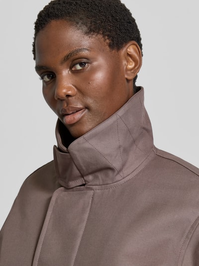 Frauenmodel trägt Jacke aus reiner Baumwolle von Victoria Beckham in Braun, glatte Textur, Stehkragen, Nahaufnahme Oberkörper. Regular Fit, Eingrifftaschen, elastische Ärmelabschlüsse, Rückenlänge bei Größe 36: 54 cm, Brustweite 50 cm, Ärmellänge 63 cm.