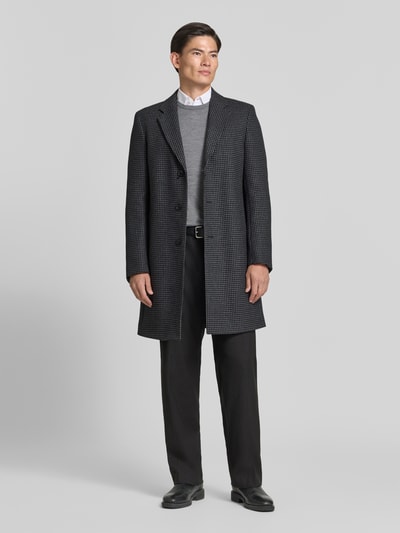 Männermodel trägt Regular Fit Wollmantel mit Allover-Muster Modell 'H-Hyde-Bib-E-264' von BOSS, dunkle Hahnentritt-Optik, Ganzkörperansicht von vorne.