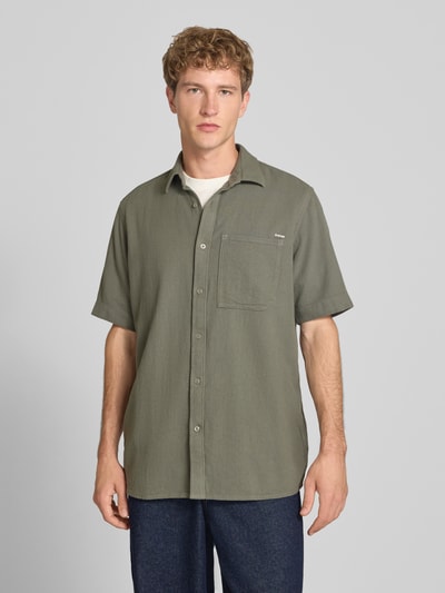 Männermodel trägt Regular Fit Freizeithemd aus reiner Baumwolle von G-Star RAW in Olivgrün mit Brusttasche, Ganzkörperansicht von vorne.
