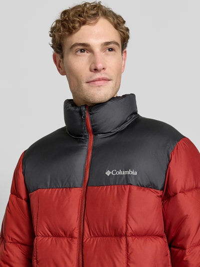 Männermodel trägt Regular Fit Jacke in Stepp-Optik Modell 'Puffect™' von Columbia in Rot und Schwarz, Nahaufnahme Oberkörper, Logo-Print, Stehkragen, Reißverschluss, Herren Jacke.