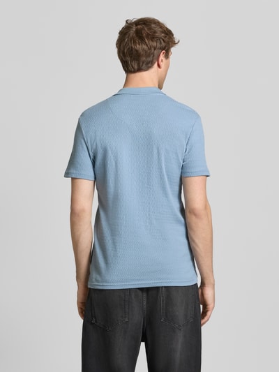 Männermodel trägt Regular Fit Polo-Shirt mit Strukturmuster Modell 'Heskild' von Blend aus reiner Baumwolle in Hellblau, Ganzkörperansicht Rückansicht.