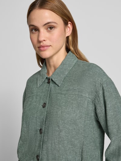 Kobiece modelka nosi zieloną Jacke aus Leinen-Mix mit Kentkragen Modell 'Viana Ginia' od MSCH Copenhagen o prostym kroju, lniana faktura z dodatkiem wiskozy, guzikowe zapięcie, długość tyłu w rozmiarze S: 53 cm, szerokość ramion w rozmiarze S: 49 cm, szerokość klatki piersiowej w rozmiarze S: 53 cm, długość rękawa w rozmiarze S: 53 cm, zbliżenie na górną część ciała