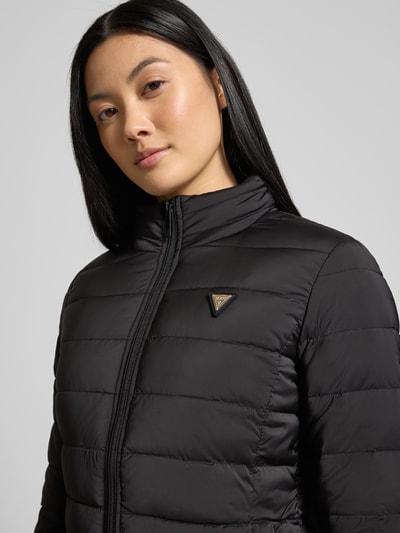 Vrouwenmodel draagt Steppjacke mit Stehkragen und Label-Detail van Guess Activewear, zwarte kleur, slim fit, materiaal-mix, Nahaufnahme bovenlichaam.