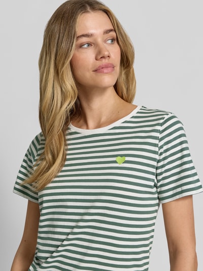 Frauenmodel trägt T-Shirt mit Motiv-Stitching und Rundhalsausschnitt von FREE/QUENT in Weiß-Grün gestreift, reine Baumwolle, Nahaufnahme Oberkörper.