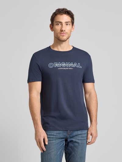 Męski model nosi Regular Fit T-Shirt aus reiner Baumwolle od Tom Tailor Denim, efekt: jednolity kolor, krój regular fit, z napisem z logo, okrągły dekolt, krótki rękaw, bawełna; zdjęcie całej sylwetki z przodu.