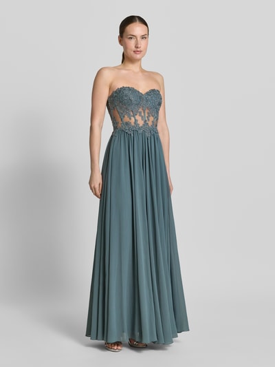 Frauenmodel trägt Abendkleid mit Spitze und Gehschlitz von Mascara in Blau, Maxikleid mit Herz-Ausschnitt und Strasssteinbesatz, semitransparent, Ganzkörperansicht von vorne.