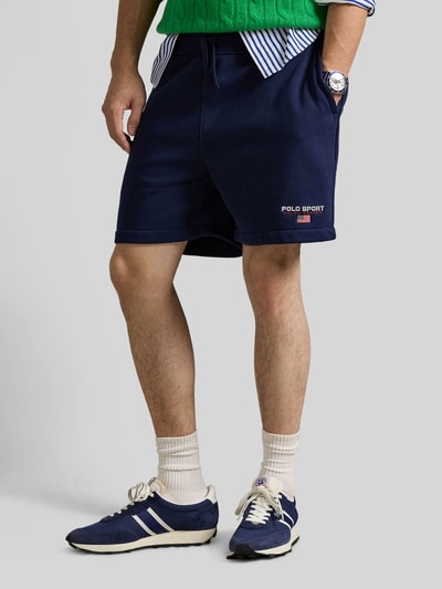 Männermodel trägt Regular Fit Sweatshorts aus Baumwoll-Mix von Polo Ralph Lauren in effen blauw met labeltekst, zijsplitzakken, elastische tailleband met tunnelkoord, sweatstof, Ganzkörperansicht von vorne.